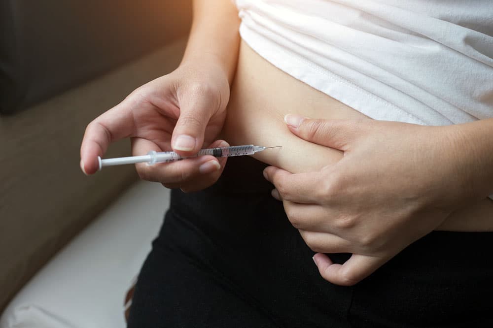Primer plano de una persona que se autoinyecta un medicamento para bajar de peso en el abdomen