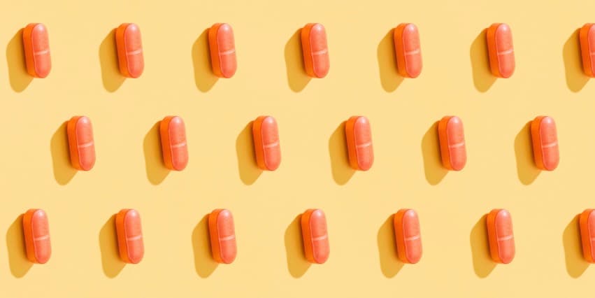 Un patrón repetitivo de pastillas anaranjadas sobre un fondo amarillo limón