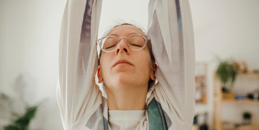 Woman doing warrior pose Portrait of a white woman wearing glasses doing yoga at home.