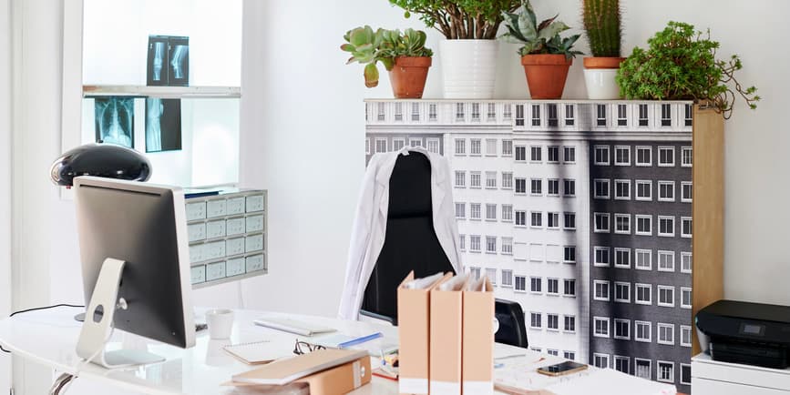Modern doctor office Computer, files and medical charts on a doctor's desk in his office with x-rays in the background