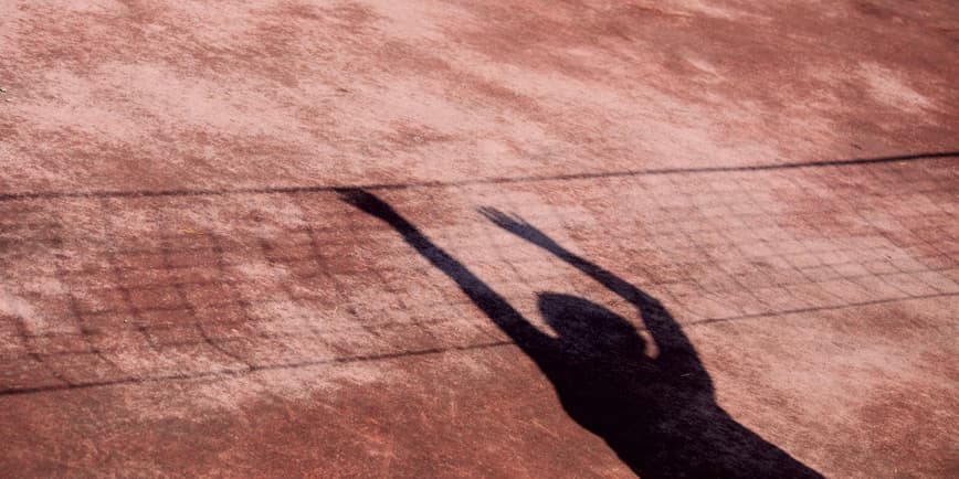 Shadow of women on tennis court net The shadow of a woman splays out on a tennis court, look like she's reaching over the net.