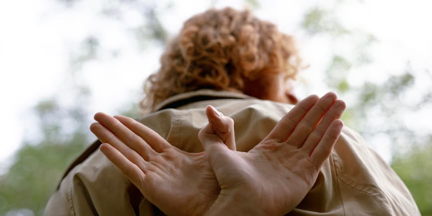 Man with hands folded behind his back A young man with curly red hair wearing a tan shirt seen from behind, with his hands behind him folded to look like wings.