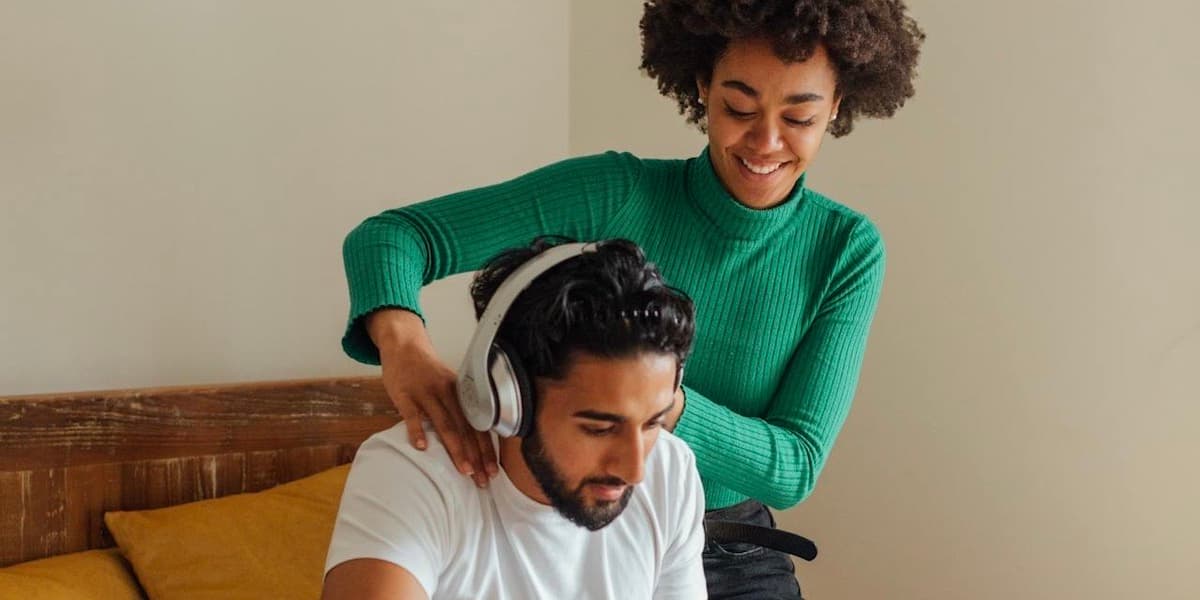 Couple on bed working and massaging A young white woman with brown hair lays covered in dark red tennis court clay as she lays on the court and laughs, a racket and balls nearby.