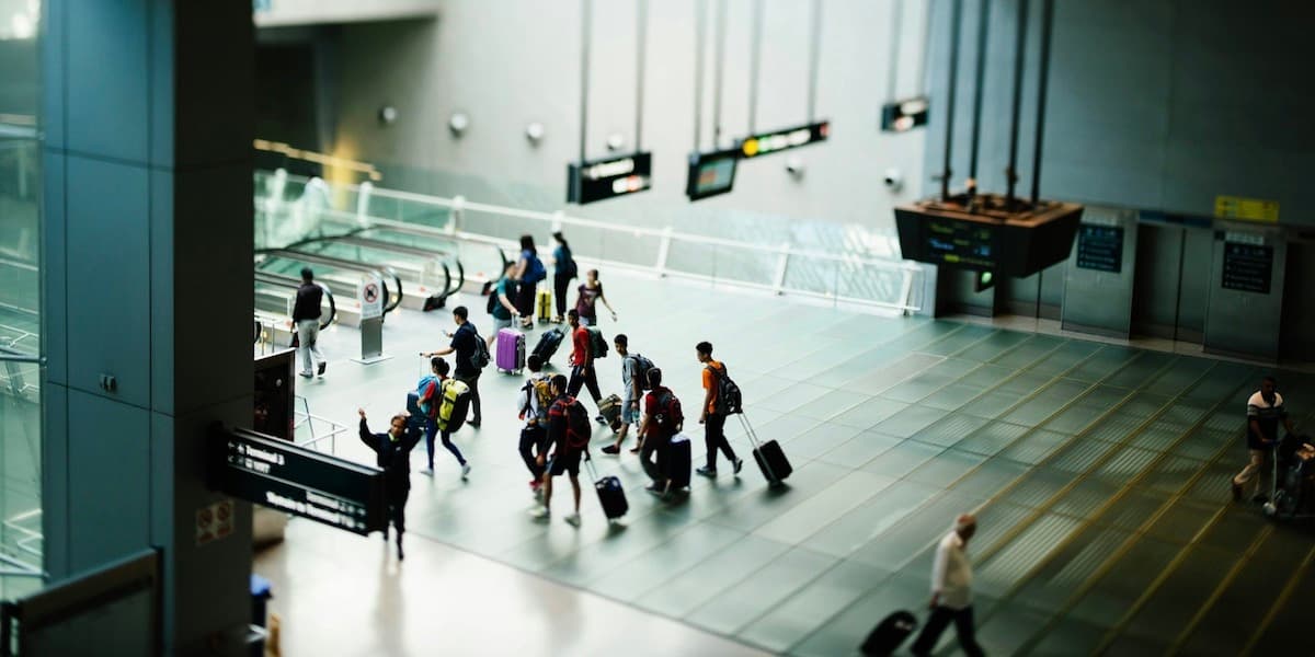 Airport interior A somewhat blurry faraway shot of an airport interior, with passengers pulling luggage to moving walkways and other areas of a terminal.