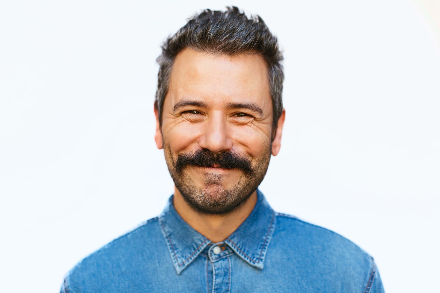 Hombre con camisa vaquera azul con barba sonriente