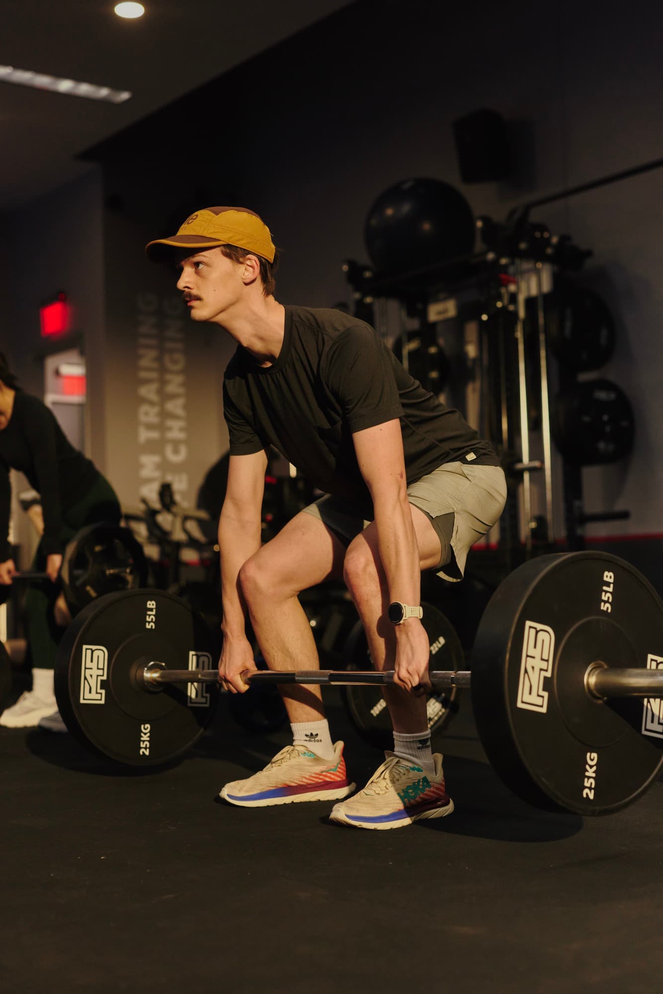 A man performs a barbell deadlift during an F45 Training workout, showcasing strength and functional movement in a modern studio.