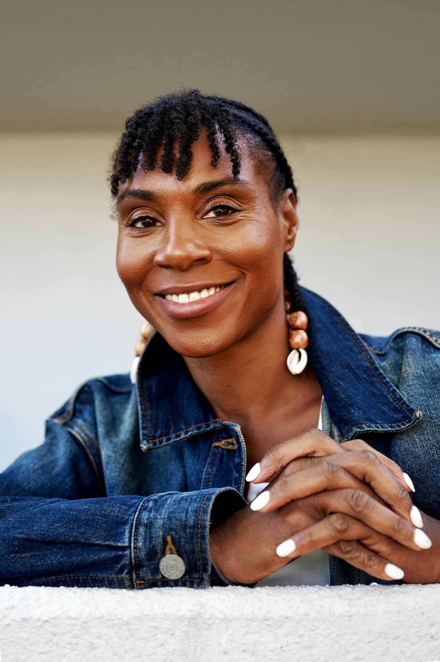 La mujer con una chaqueta vaquera sonríe con tranquila confianza y seguridad en sí misma, relajada y a gusto